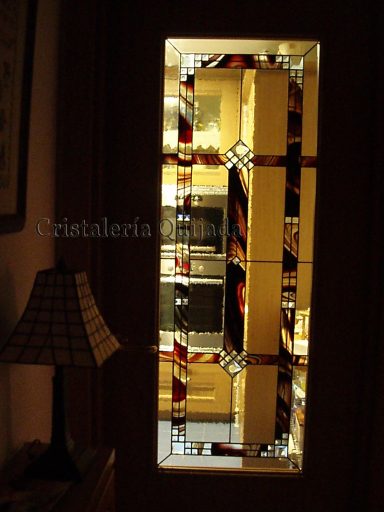 Vidriera barroca Ventana de vitral con colores cálidos y patrones geométricos, iluminada desde el interior.