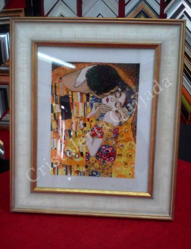 Punto de cruz. "El Beso" de Gustav Klimt Reproducción de obra artística enmarcada, con figuras en colores vibrantes y fondo dorado.